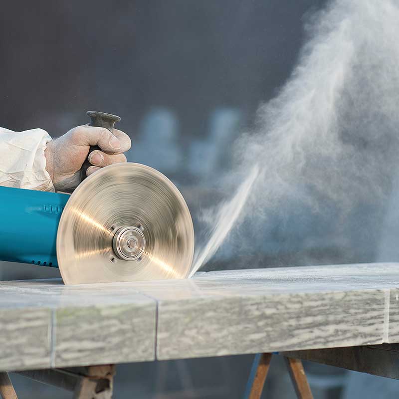 Arbeiter schneidet Steinschleifmaschine