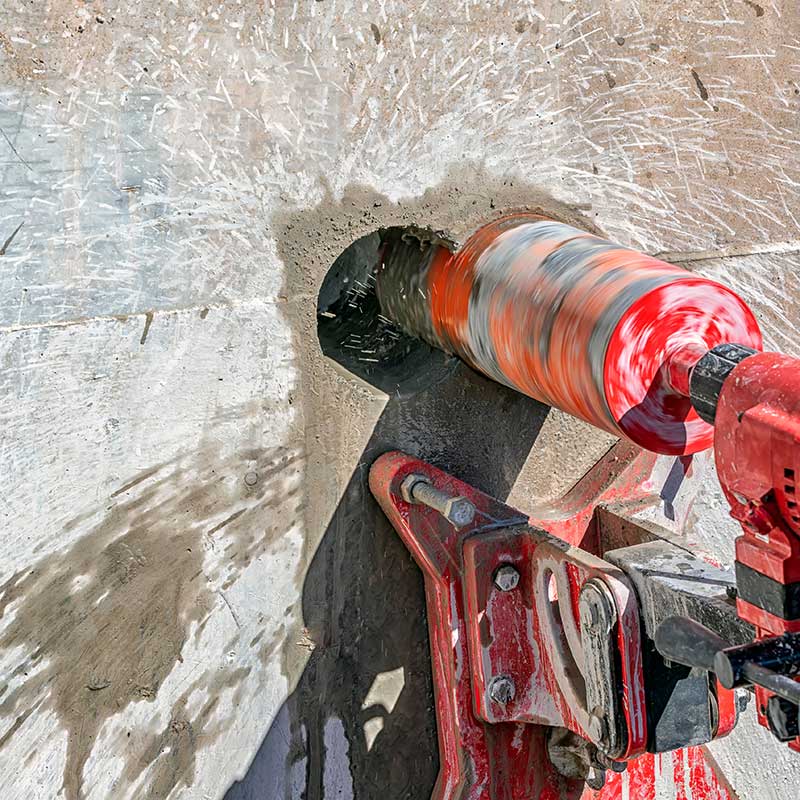 Arbeiter bohrt mit Kernbohrmaschine an Betonwand. Kernbohrer in Metall werden Kernbohrer genannt. Kernbohrer für Beton und Hartgestein verwendeten im Allgemeinen industrielle Diamantkörnung